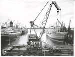 Title
Auckland Wharves

Publicity Caption
Huge floating crane just to the right of Admiralty steps. Queens wharf on left, Captain Cook wharf on right. Traffic on Quay street in foreground.

Photographer
Mr. Riethmaier.
