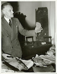 Title
Captain Cook Relics

Publicity Caption
After Captain James Cook had been killed by natives at Kealakekua Bay, Hawaii, in 1779 officers of his expedition recorded the circumstances on a copper plate fixed to the stump of a coconut palm. Here Dr. R.A. Falla, Director of the Dominion Museum, Wellington, holds a section of that palm, given to the Museum by the Royal Librarian at Windsor Castle. It accompanied Her Majesty The Queen's collection of Cook relics, formerly held in the Imperial Institute, London, and now on indefinite loan with the Dominion Museum. The souvenirs, some of which are seen in the picture, will probably be on display later at other New Zealand centres.

Photographer
E. Woollett.