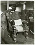 Title
The chair is that used by Sir Charles Clifford, first Speaker of the House of Representatives. After the transfer of the seat of Government from Auckland to Wellington, the chair continued to be used by speakers of the Auckland Provincial Council.

Publicity Caption
In a simple ceremony at the General Assembly Library in Parliament Buildings on July 26, 1955, the Speaker of the House of Representatives, Sir Matthew Oram, accepted from the Mayor of Auckland, Mr. J. H. Luxford, the original Speaker's Chair, and the historic seals of New Zealand and of the original provinces of New Munster and New Ulster, for "safe keeping" in the library. The Prime Minister, Mr. Holland, also unveiled a Coronation vase similar to that presented to the Queen by the British Pottery Manufacturers' Association. The vase, given to New Zealand by the Manufacturers, is in a special showcase, accompanied by ornate cases containing the freedoms of British cities presented to New Zealand Prime Ministers while overseas.

Photographer
B. Clark.