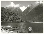 Title:
Fishing - Trout

Publicity Caption:
Peter Donaghy, fishing guide with the Hollyford Tourist and Travel Co. holding a brown trout he has just caught in Lake McKerrow. The Darran Range in the background, Fiordland National Park, Otago

Photographer:
R. Anderson