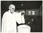 Title:
Churches

Publicity Caption:
Archdeacon Pearson, Vicar of St John's Anglican Church, pours water into the font

Photographer:
R Anderson