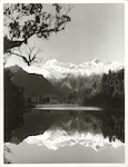 Title:
Westland - Matheson, Lake

Publicity Caption:
Lake Matheson, Mt. Tasman (at left) together with Mt. Cook (at right) mirrored in the reflections of the Lake

Photographer:
M. Berthold