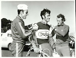 Title: 
Sports - Cycling

Publicity Caption:
Dulux Six Day Cycle Race: Fausto de Maria (New Caledonia) and Lou Driver (Auckland) attach race number to Jean Louis Clemen prior to start of Dulux Six Day Cycle Race

Photographer:
Riethmaier