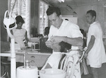 Title: 
Pacific Island - Cook Islands - Rarotonga - Health

Publicity Caption:
The Cook Islands, since 1901 a territory of New Zealand, attained internal self-government on August 4, 1965. The 20,000 inhabitants of this scattered South Pacific group, however, remain New Zealand citizens, while the former administrating country retains responsibility for the Islands' defence and External Affairs. Far all school children, and also for hospital in-patients, dental treatment is free. Qualified dentists based in Avarua, capital of the Cook Islands, on Rarotonga, travel from there to all parts of the group. Here is a typical scene in the dental clinic at Avarua, with Mr Kaa Henry a fully qualified dentist in attendance. 

Photographer:
Unidentified