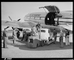 CAPTION: Rail-Air operation at Paraparaumu. Use of Curtiss C47 'Commando' Aircraft on charter from Civil Air Transport. Loading ramp attached to motor forklift with small car about to be loaded. General view.

PHOTOGRAPHER: J.G. Duncan

DATE: 22 May 1951
